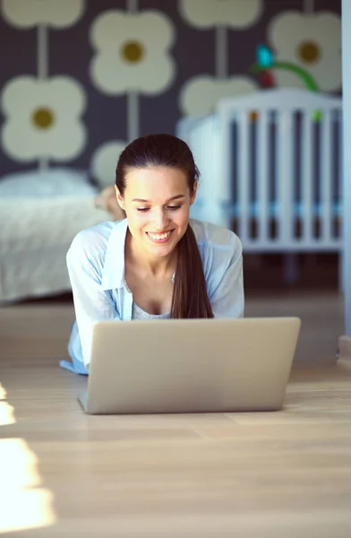 Unga vackra kvinnan hemma sitter på golvet med laptop — Stockfoto