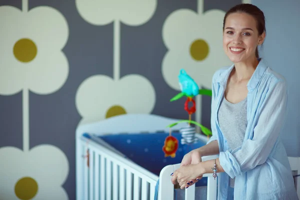 Ung vacker kvinna som står nära barn barnsäng — Stockfoto