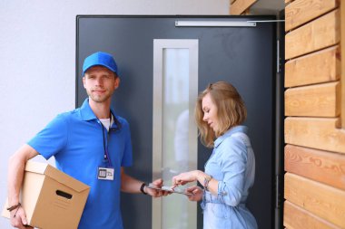 Mavi üniformalı gülümseyen kurye servis konseptine paket kutusu teslim eden teslimatçı.