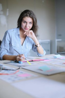 Dizüstü bilgisayar ekranına bakarak office tablosunda oturan genç kadın