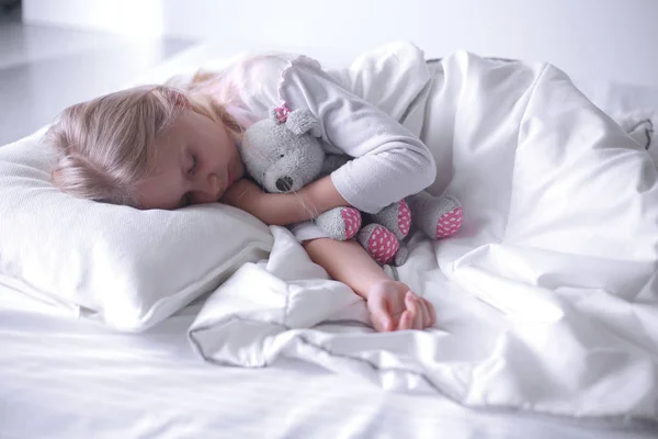 Child little girl sleeps in the bed with a toy teddy bear — Stock Photo, Image