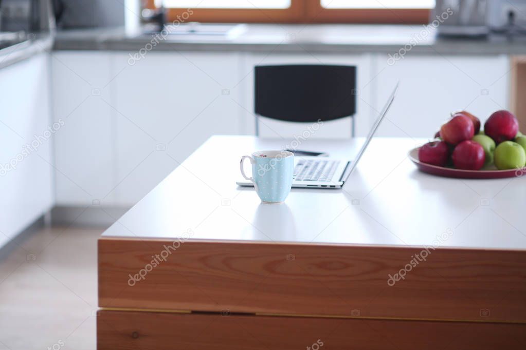 Laptop white screen and coffee cup on marble table with kitchen background