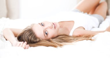Güzel bir kadın yatağında uzanıyor.