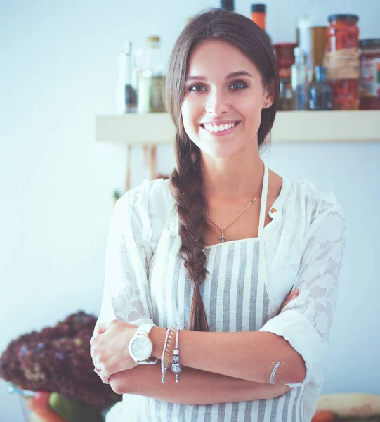 Mujer joven de pie cerca de escritorio en la cocina — Foto de Stock