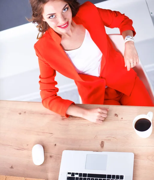 Mulher atraente sentada na mesa no escritório, trabalhando com computador portátil — Fotografia de Stock