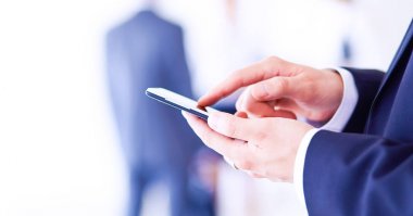 Ofisteki genç iş adamının portresi. Arka planda meslektaşları var ve cep telefonu kullanıyor.