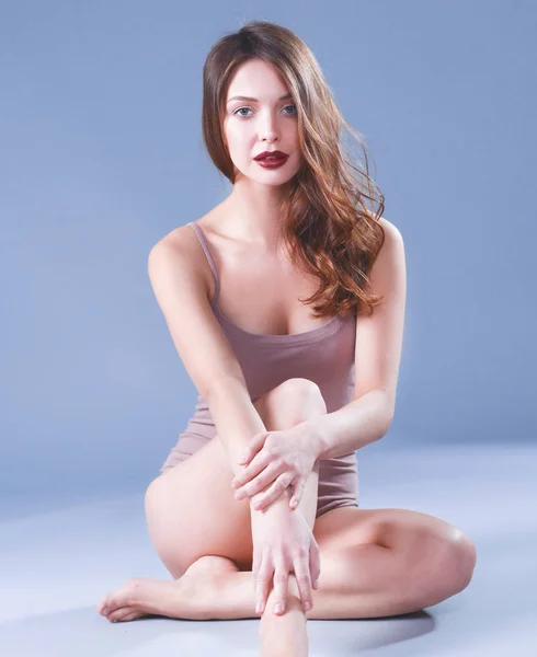 Schöne barfüßige Frau, die auf dem Boden sitzt — Stockfoto