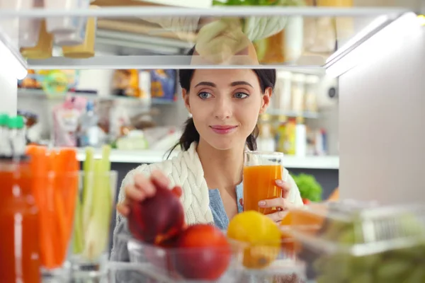 Portrait of female standing near open fridge full of healthy food, vegetables and fruits — Stock Photo, Image