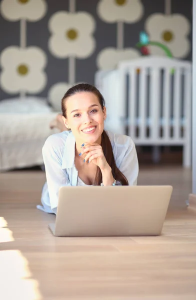 Unga vackra kvinnan hemma sitter på golvet med laptop — Stockfoto