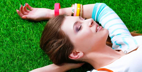 Mooie jonge vrouw liggend op groen gras — Stockfoto