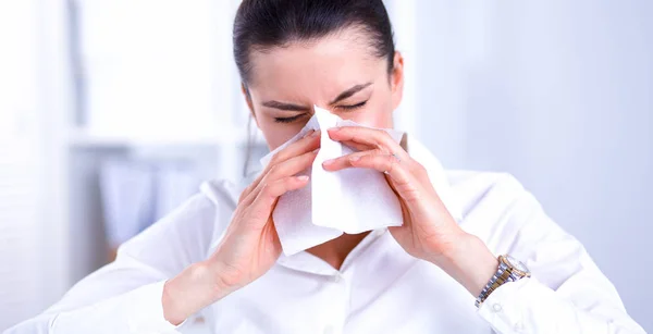 Young businesswoman blowing her nose, sits at the desk — Stock Photo, Image