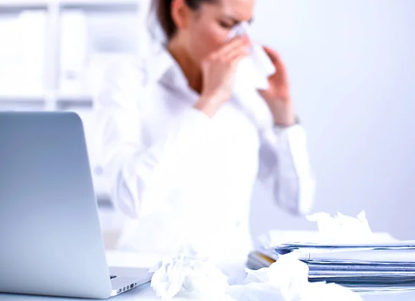 Młoda bizneswoman dmuchając nos, siedzi przy biurku — Zdjęcie stockowe