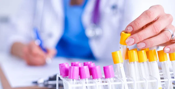 Kvinnlig forskare är omgiven av medicinska flaskor och kolvar — Stockfoto