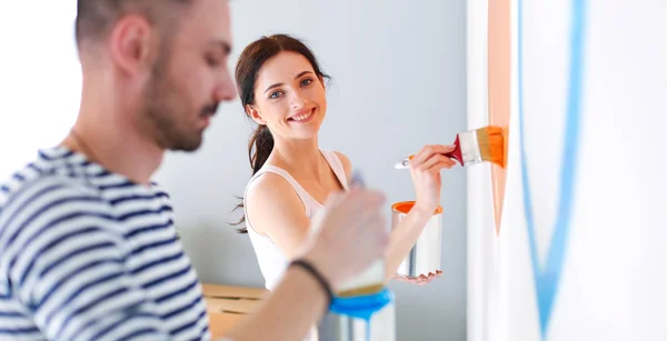 Retrato feliz sorrindo jovem casal pintura parede interior da nova casa — Fotografia de Stock