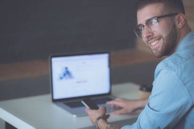 Genç adam kullanarak telefon ve dizüstü bilgisayarda çalışır