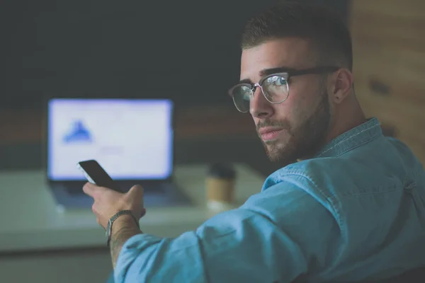 若い男を使用して携帯電話し、ラップトップ上で動作 — ストック写真