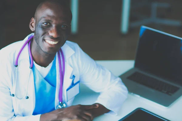 机の上でノートパソコンで働く若いアフリカ人医師 — ストック写真