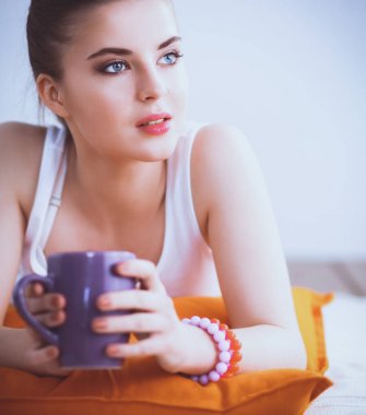 Yastık ile bir yerde yatarken gülümseyen genç kadın