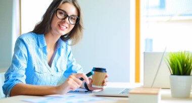 Dizüstü bilgisayar ekranına bakarak office tablosunda oturan genç kadın