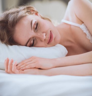Güzel bir kadın yatağında uzanıyor.