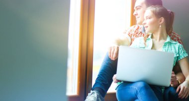 Dizüstü bilgisayar ile pencere evde oturan hareketli Çift