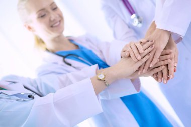 Doktorlar ve hemşireler tıbbi bir ekipte el ele tutuşuyorlar.