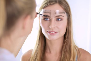 Kaşlar için kalıcı makyaj. Güzellik salonunda kalın kaşlı güzel bir kadın.