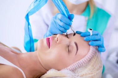 Kaşlar için kalıcı makyaj. Güzellik salonunda kalın kaşlı güzel bir kadın.