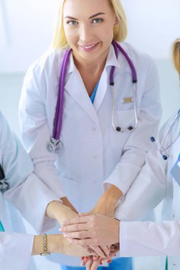 Doktorlar ve hemşireler tıbbi bir ekipte el ele tutuşuyorlar.