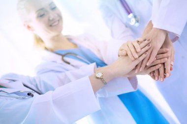 Doktorlar ve hemşireler tıbbi bir ekipte el ele tutuşuyorlar.