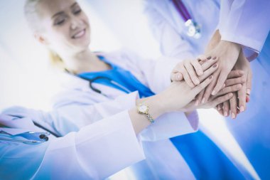 Doktorlar ve hemşireler tıbbi bir ekipte el ele tutuşuyorlar.