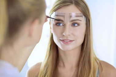 Kaşlar için kalıcı makyaj. Güzellik salonunda kalın kaşlı güzel bir kadın.