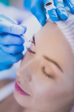 Kaşlar için kalıcı makyaj. Güzellik salonunda kalın kaşlı güzel bir kadın.