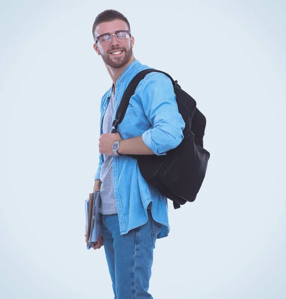 Jonge mannelijke student met schooltas houden boeken geïsoleerd op witte achtergrond — Stockfoto