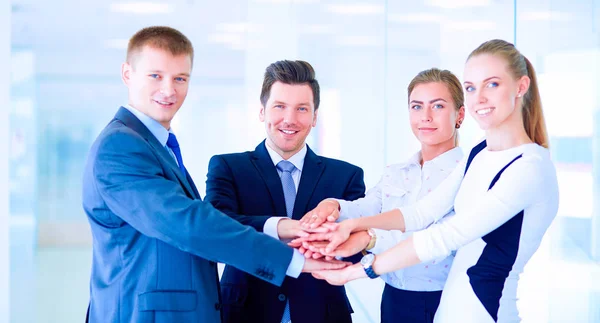 Business team joining hands together standing in office — Stock Photo, Image