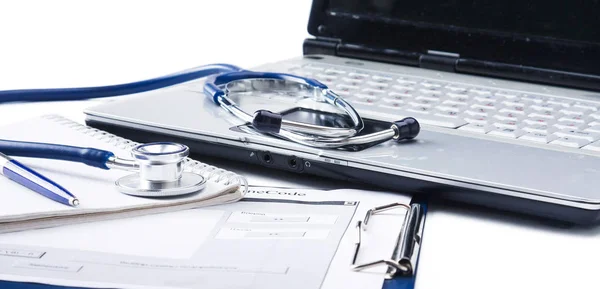 Stéthoscope avec presse-papiers et ordinateur portable sur le bureau — Photo