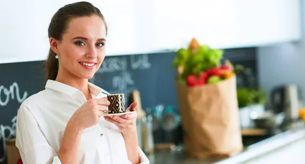 Jonge vrouw met tablet in de keuken thuis en het drinken van koffie — Stockfoto