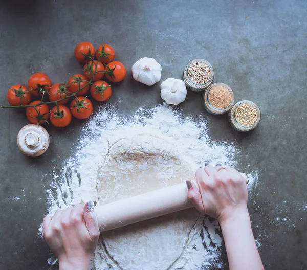 Güzel bir kadın mutfakta pasta pişiriyor. Masanın yanında duruyor.