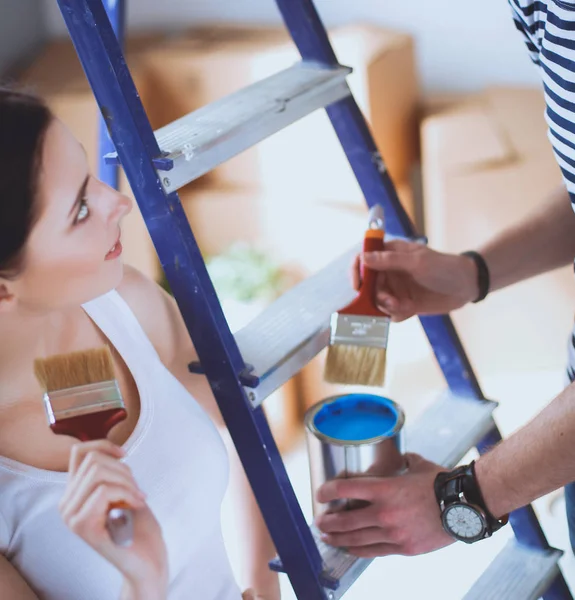 Portrait heureux sourire jeune couple peinture mur intérieur de la maison neuve — Photo