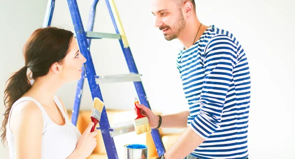 Retrato feliz sorrindo jovem casal pintura parede interior da nova casa — Fotografia de Stock