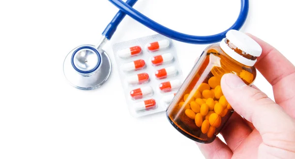Flaskor med piller och en medicinsk stetoskop på vit bakgrund — Stockfoto