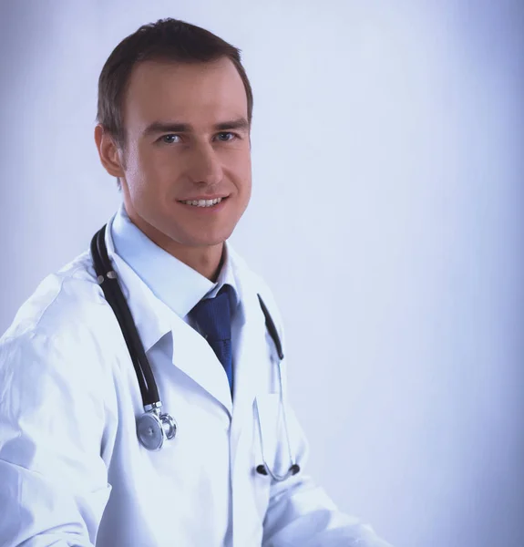 Junger Arzt sitzt am Tisch auf hellem Hintergrund — Stockfoto