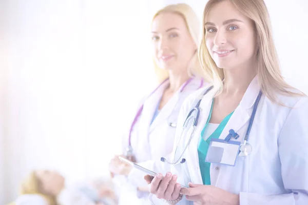 Retrato de tres doctores confiados de pie con los brazos cruzados en el consultorio médico — Foto de Stock