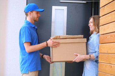 Mavi üniformalı gülümseyen kurye servis konseptine paket kutusu teslim eden teslimatçı.