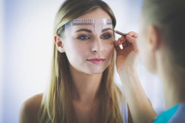 Kaşlar için kalıcı makyaj. Güzellik salonunda kalın kaşlı güzel bir kadın.