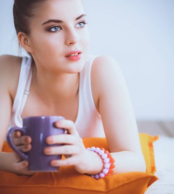 Yastık ile bir yerde yatarken gülümseyen genç kadın