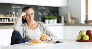 Tablette tarifi takip eden bir kadın evde yemek pişiriyor.