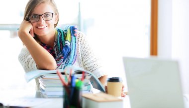 Kitapların arasında masa başında oturan genç bir kadın.