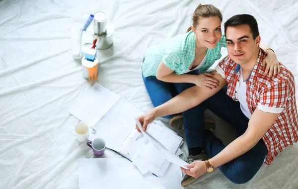 Jovem casal sentado no chão com plano de apartamento — Fotografia de Stock