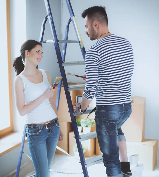 Portrait happy smiling young couple painting interior wall of new house — Stock Photo, Image